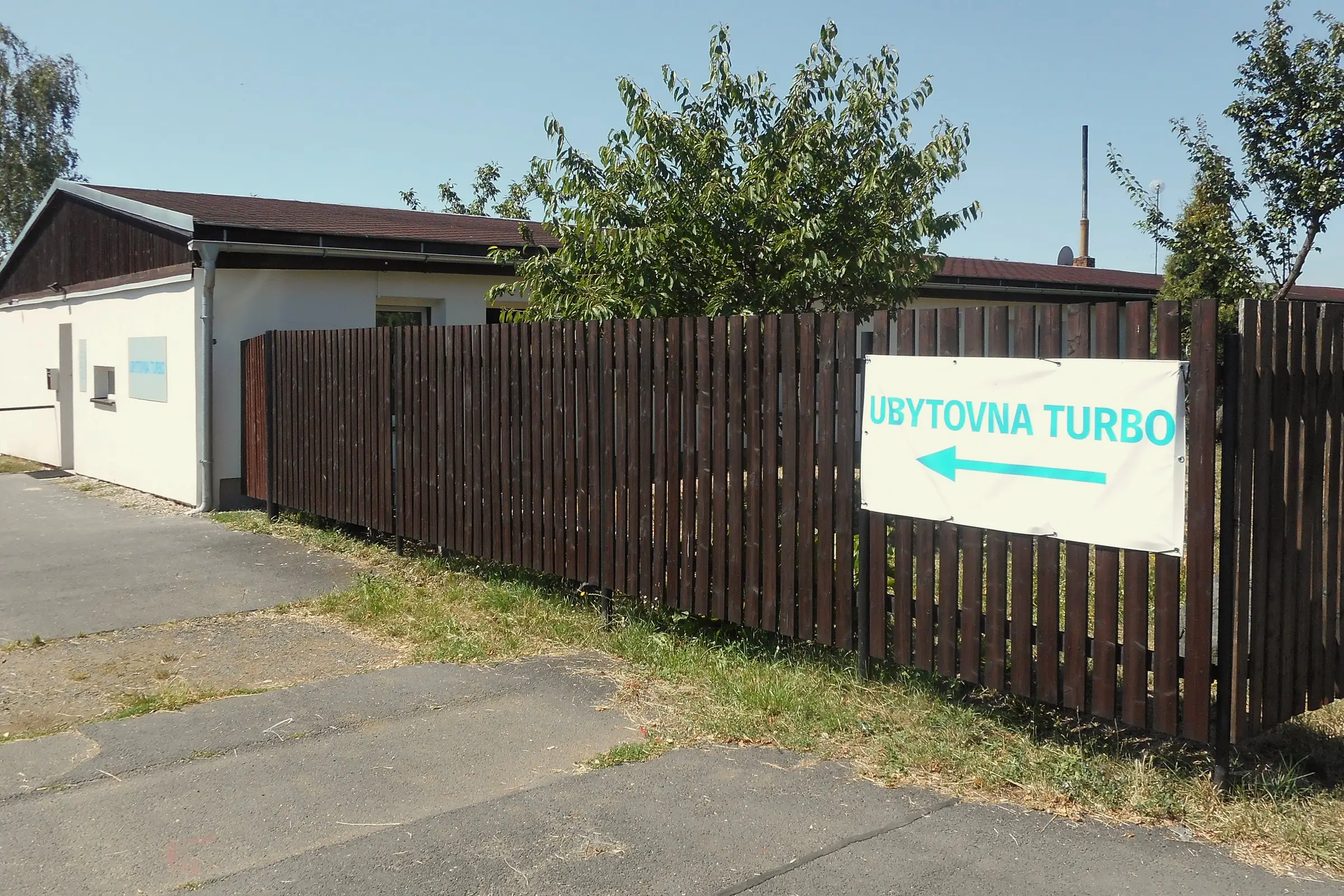 Budova VS ubytovny s cedulí na plotě, ulice Kosmonautů v Chomutově